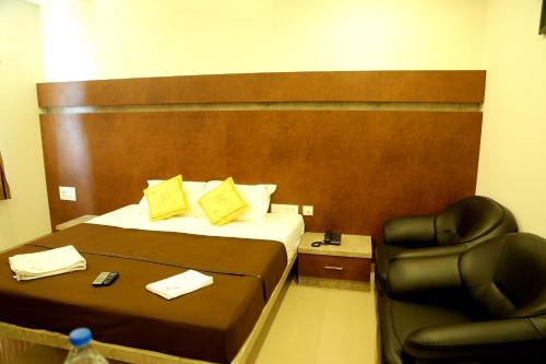 a hotel room with a bed and a chair at Samarth Residency in Hospet