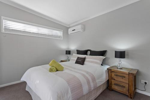 a bedroom with a large white bed and a window at Pandanus Spa Cottage in Coolum Beach