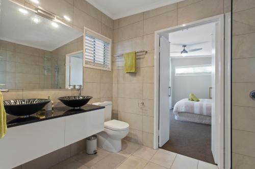 a bathroom with two sinks and a toilet and a bed at Pandanus Spa Cottage in Coolum Beach
