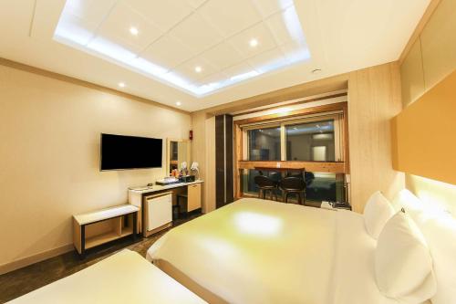 a hotel room with a bed and a television at Hotel TopsVille in Gangneung