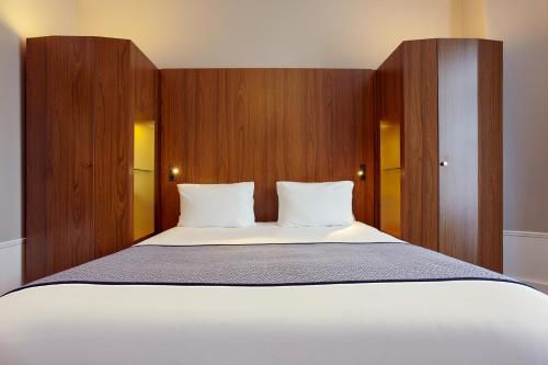 una camera da letto con un grande letto bianco con pannelli in legno di Holiday Inn Paris - Gare de Lyon Bastille by IHG a Parigi