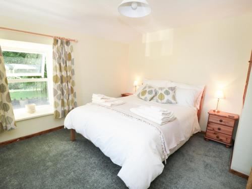 1 dormitorio con cama blanca y ventana en Rose Cottage, en Chinley