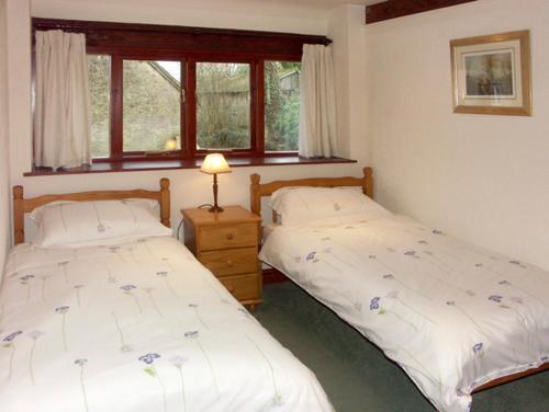 ジリンガムにあるBrook Cottageのベッドルーム1室(ベッド2台、ランプ、窓2つ付)