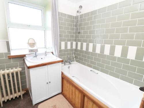 a bathroom with a bath tub and a sink at Rose Cottage in Chinley