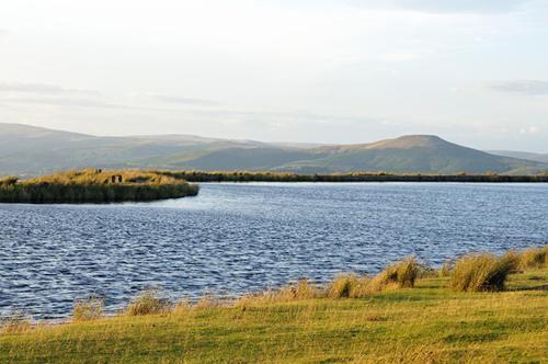 uma grande massa de água com montanhas ao fundo em The Byre em Abergavenny