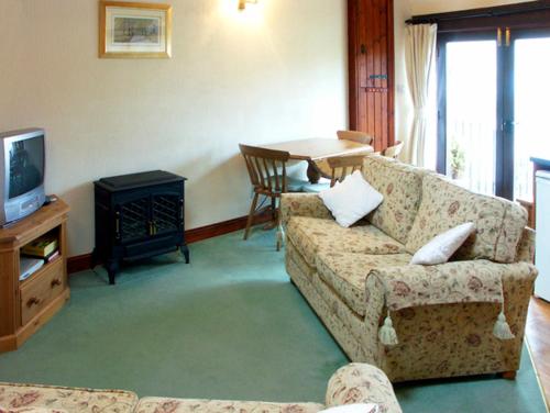 a living room with a couch and a tv and a table at Brook Cottage in Gillingham