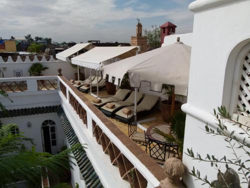 a balcony of a building with chairs and umbrellas at Riad Palais Des Princesses & Spa in Marrakesh