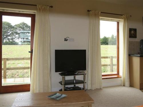 a living room with a flat screen tv and windows at Lodge Cottage in York