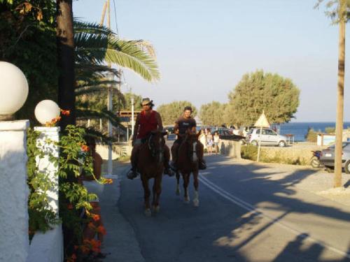two people are riding horses down a street at Seaside Studios Kirania in Kiotari
