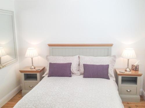 a bedroom with a large white bed with two lamps at The Hideaway in Verwood