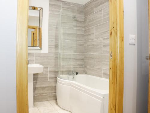 a bathroom with a white tub and a sink at Gardener's Lodge in Nantwich