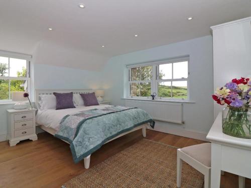 a white bedroom with a bed and two windows at The Old Forge, St Just in St. Just