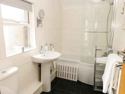 a white bathroom with a sink and a bath tub at Marina View in Whitby