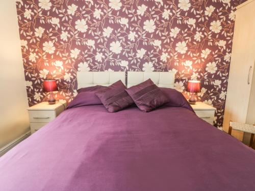 a bedroom with a purple bed with flowers on the wall at Quarterdeck in Scarborough