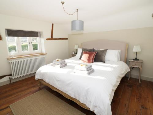 a bedroom with a white bed with towels on it at Ivy Cottage in Great Malvern