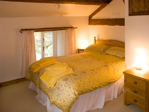 BuckdenにあるGrange Cottageのベッドルーム1室(黄色いシーツ付きのベッド1台、窓付)