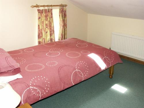 a pink bed in a room with a window at The Coach House in Hereford