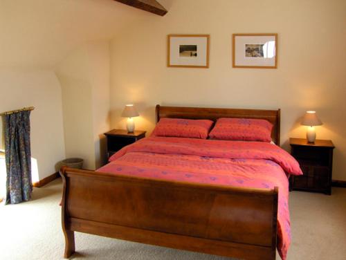 ein Schlafzimmer mit einem Bett mit roter Bettwäsche und zwei Lampen in der Unterkunft The Coach House in Shrewsbury