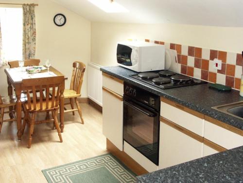 a kitchen with a stove and a table with a microwave at The Coach House in Hereford