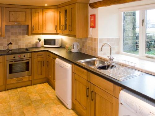 BuckdenにあるGrange Cottageのキッチン(木製キャビネット、シンク、食器洗い機付)