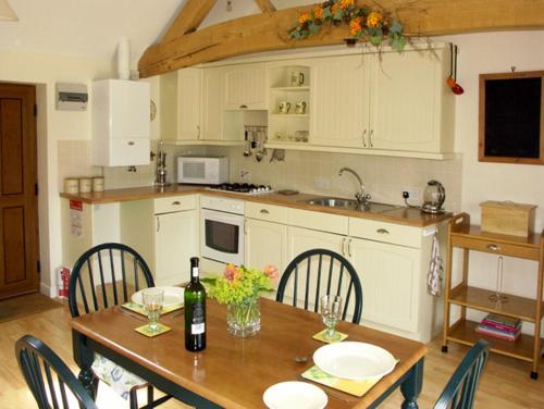 a kitchen with a wooden table with chairs and a bottle of wine at The Byre in Bishops Castle