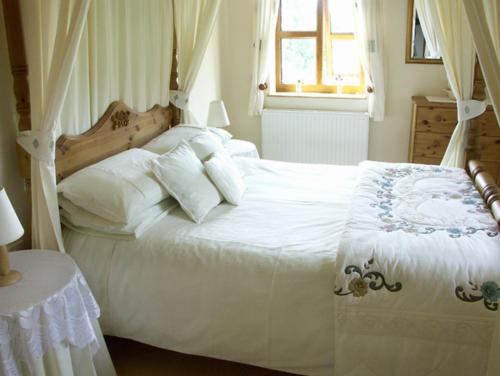 a bedroom with a white bed and a window at The Byre in Bishops Castle