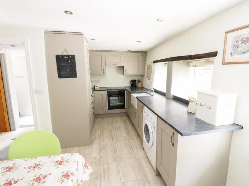 a kitchen with white appliances and a green chair at Orchard Cottage in Lothersdale