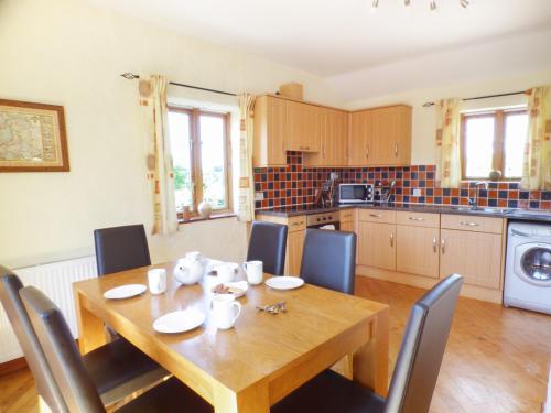 a dining room table with chairs and a kitchen at The Old Granary in Haverfordwest