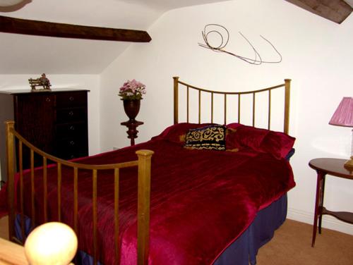 LanchesterにあるProspect Cottageのベッドルーム1室(木製ベッド1台、赤い掛け布団付)