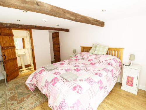 a bedroom with a bed with a pink and white comforter at Orchard Cottage in Lothersdale