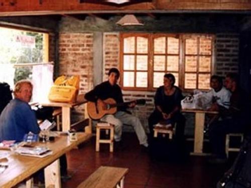 un grupo de personas sentadas en una habitación tocando la guitarra en Puma Hostel en San Martín de los Andes