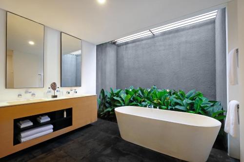 a bathroom with a tub and a large plant at Origin Ubud in Ubud