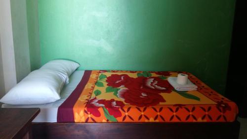 a bed in a green room with a colorful blanket at Antonio's Pension House in Dipolog