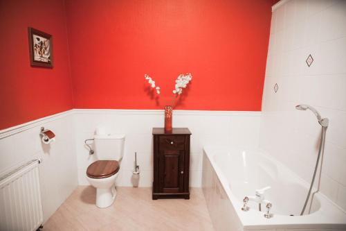 a red bathroom with a toilet and a bath tub at Noce i Dnie Hotel in Konstancin-Jeziorna