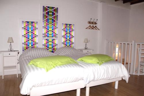 a white bed in a room with two stained glass windows at Relais de la Renaissance in Saint-Michel-de-Montaigne