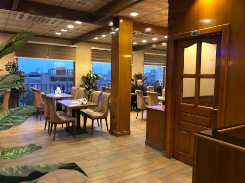 a restaurant with tables and chairs and people in the background at Castle Hotel in Al Başrah