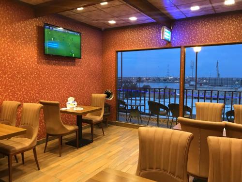 a restaurant with tables and chairs and a television on the wall at Castle Hotel in Al Başrah