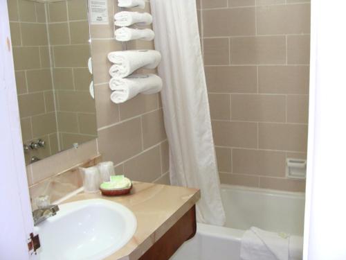 y baño con lavabo y bañera con toallas. en Lion Motel en Long Sault