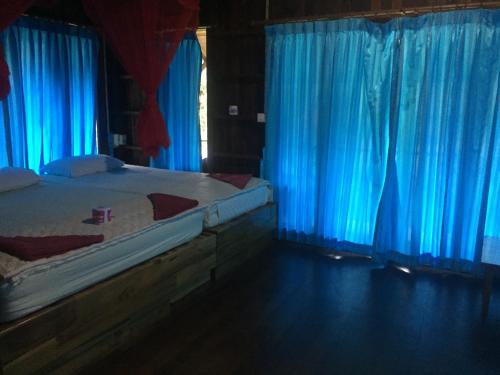 a bedroom with blue curtains and a bed at Bamboo House in Khao Sok