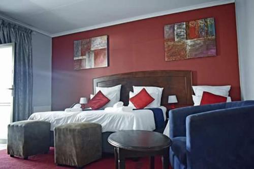 een slaapkamer met een groot bed met rode muren bij Ehrlichpark Lodge self catering and spa in Bloemfontein