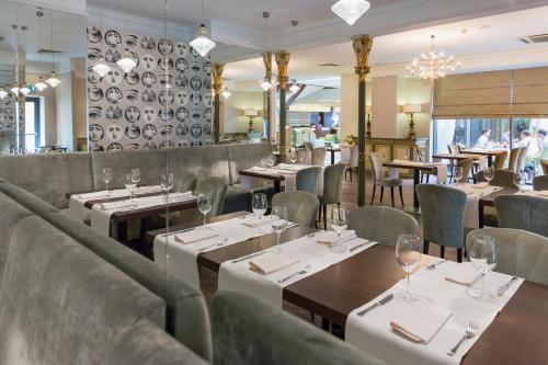 a restaurant with tables and chairs and a wall with plates at Capital Plaza Hotel in Bucharest