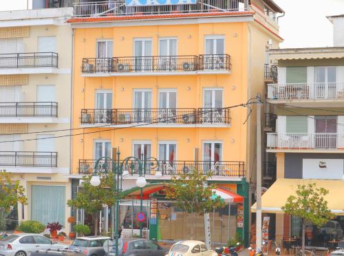 a tall yellow building with cars parked in front of it at Akti Hotel in Limenas