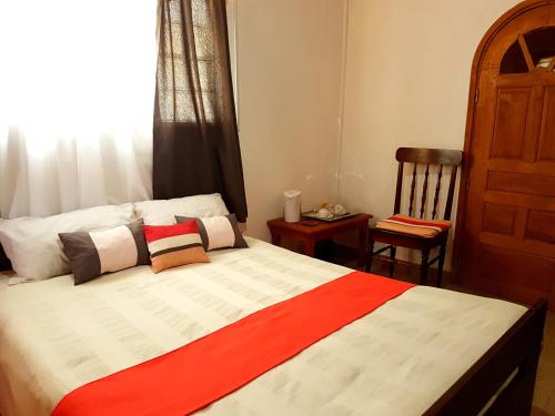 a bedroom with a bed with a chair and a window at Hotel le Trianon in Antsirabe