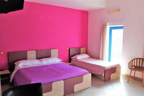 a bedroom with two beds and a pink wall at basilicata al volo in Brindisi di Montagna