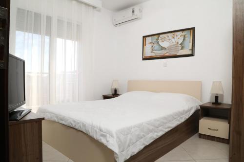 a white bedroom with a bed and a television at Sinanis Family Apartments in Keramotí