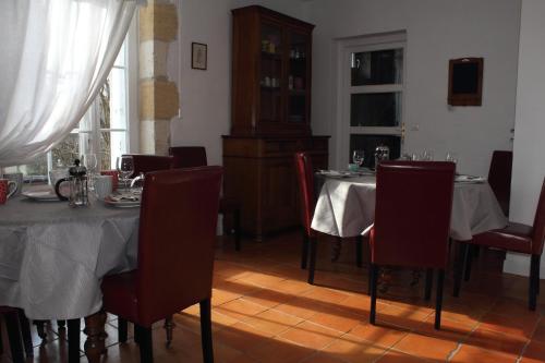 un comedor con 2 mesas con sillas rojas en Relais de la Renaissance, en Saint-Michel-de-Montaigne