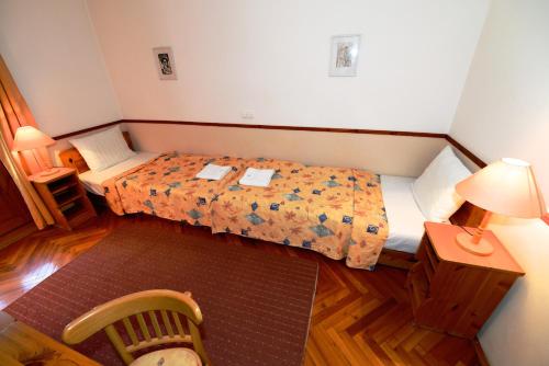 a small bedroom with a bed and a table and a lamp at Bakony Hotel in Bakonybél