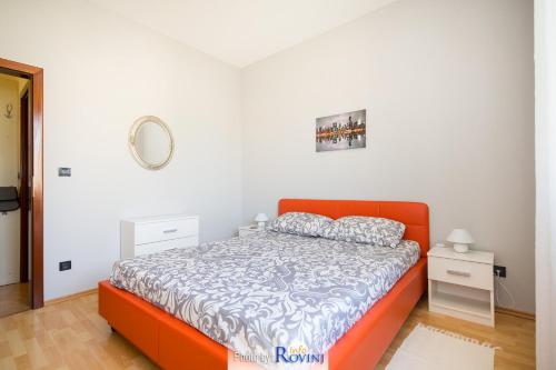 una camera con un letto arancione e una parete bianca di Zora City a Rovigno (Rovinj)
