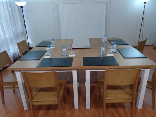 a wooden table with four chairs and water bottles on it at Hotel Marqués de Santillana in Torrelavega