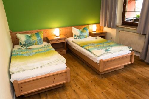 two beds in a room with green walls and wooden floors at Landgasthof Neitsch in Schwarzenberg